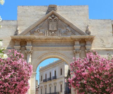 Lecce, Italy - city in Salento peninsula. Oleander flowers and Porta Napoli Triumphal Arch.